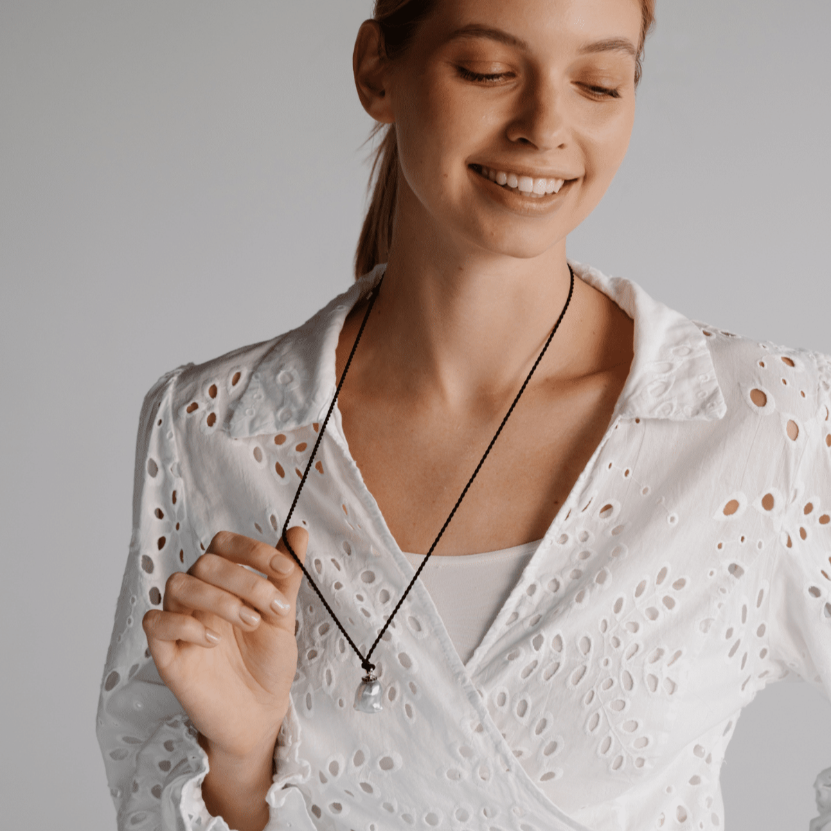 A woman wears her stunning Stella Pearl Pendant featuring a Cygnet Bay (WA) grown Australian South Sea pearl complemented by 17 Black Diamonds set in gold, delicately hung on a 100% black Silk Cord Rope.