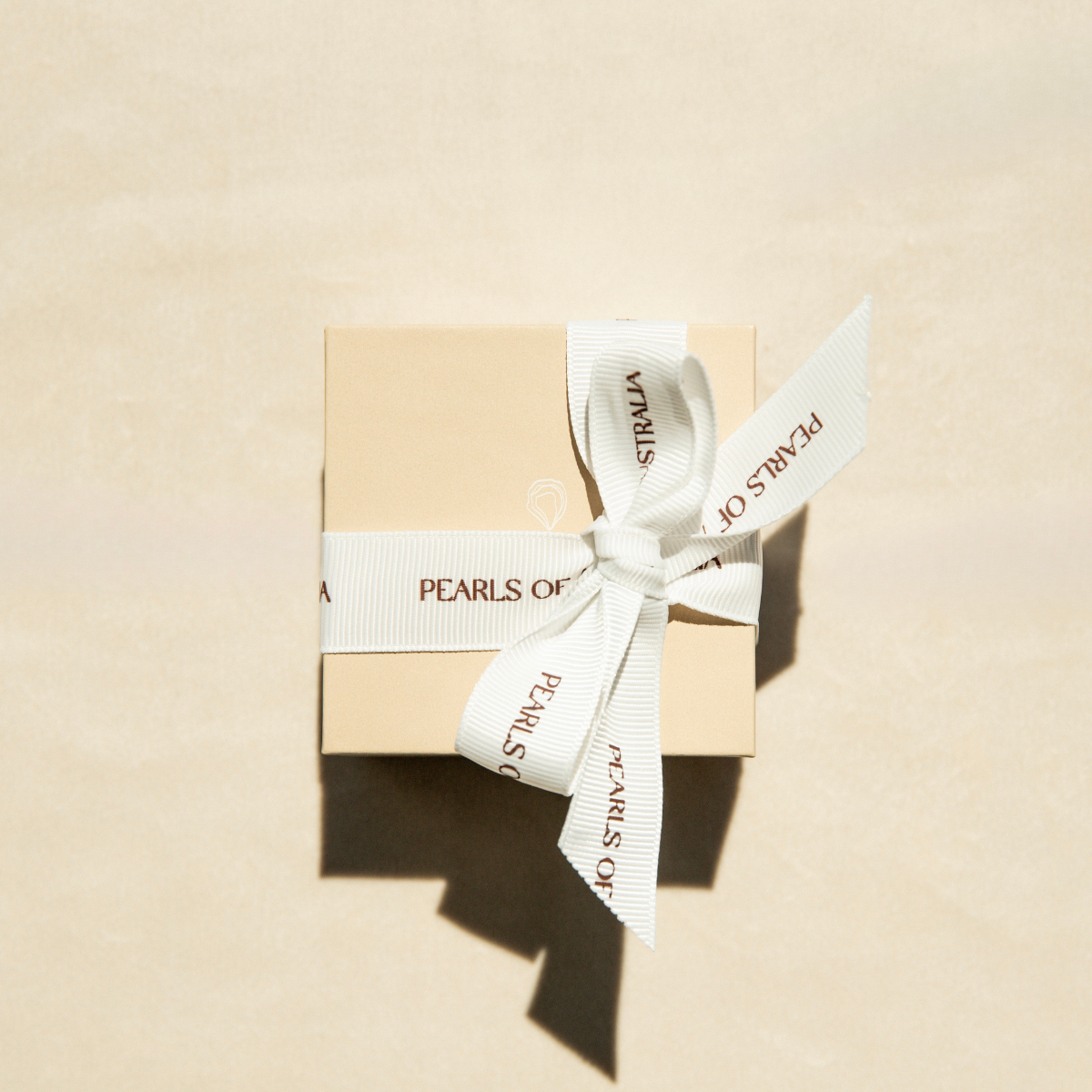Pearls of Australia beige gift box with a white ribbon on a beige background