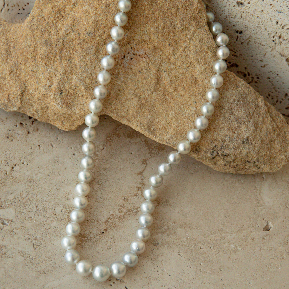 Pearl strand necklace on a textured stone surface