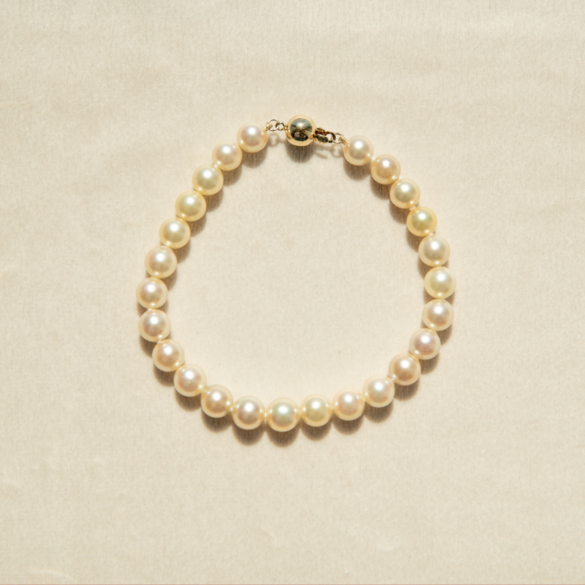 Pearl strand bracelet on a beige background