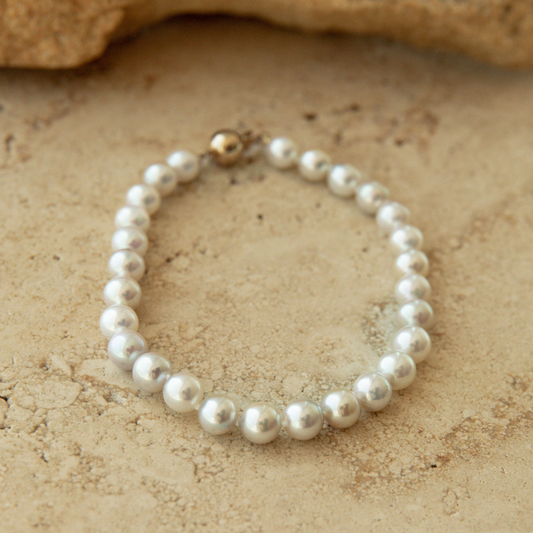 Pearl bracelet on a textured beige surface