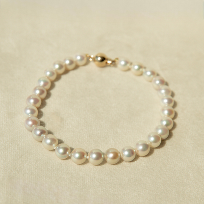 Pearl bracelet with a gold clasp on a beige background