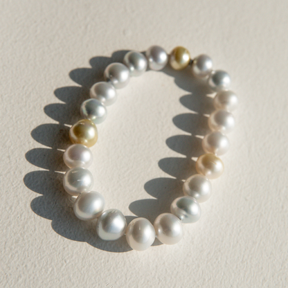 Pearl strand bracelet with gold accents on a light beige background
