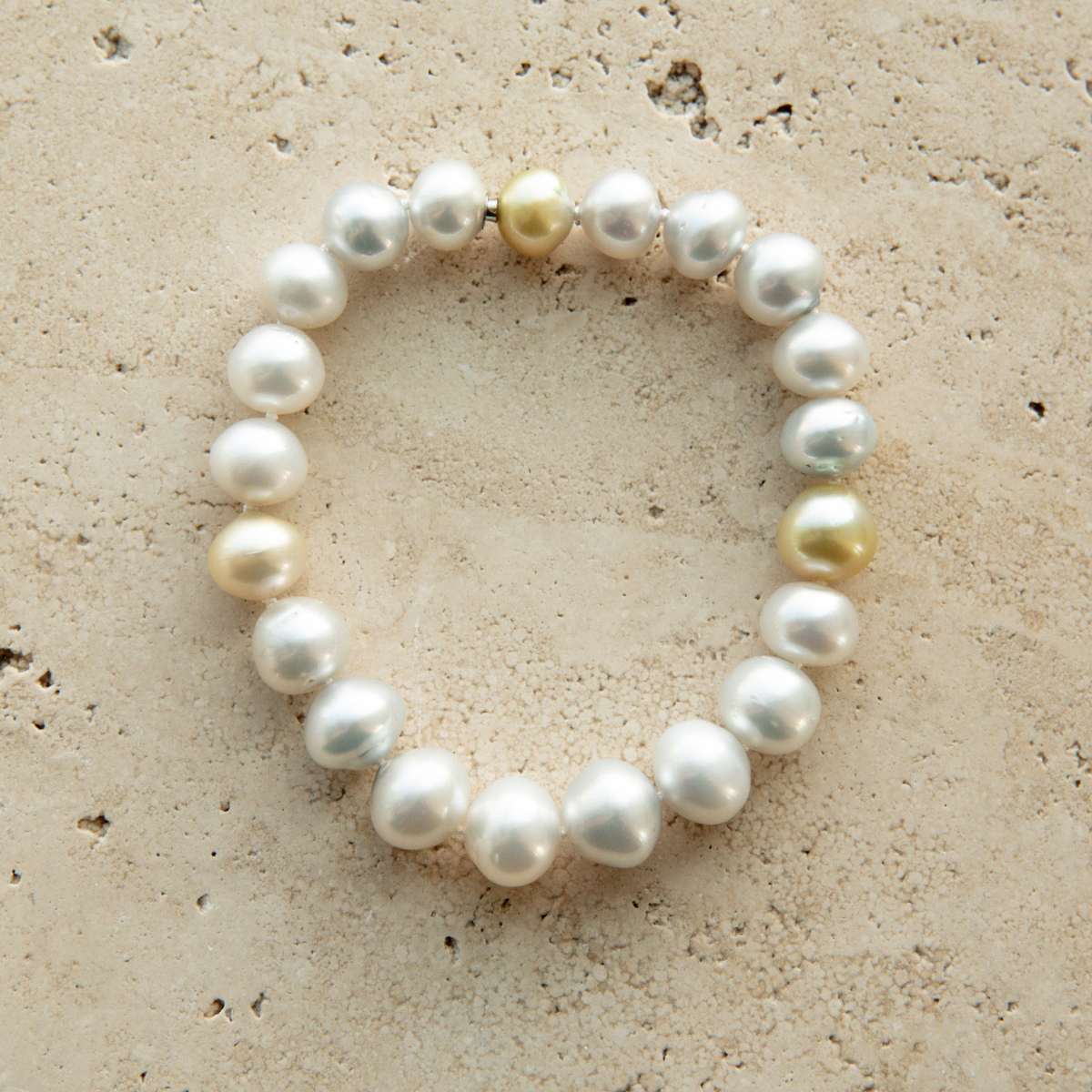 Pearl strand bracelet on a textured beige surface