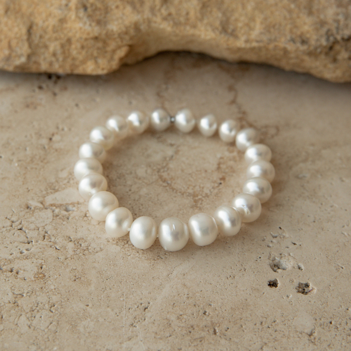 Pearl strand bracelet on a textured stone surface