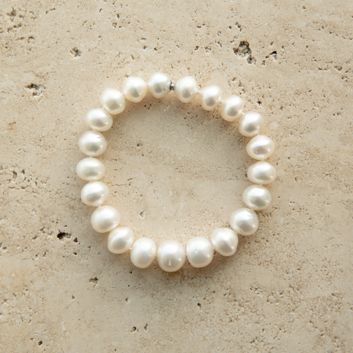 Pearl strand bracelet on a textured beige surface