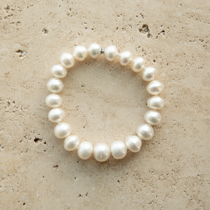 Pearl strand bracelet on a textured beige surface