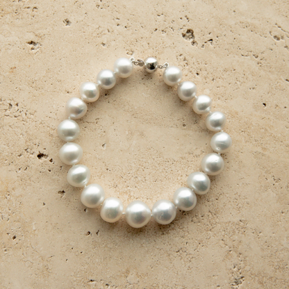 Pearl strand bracelet on a textured beige surface