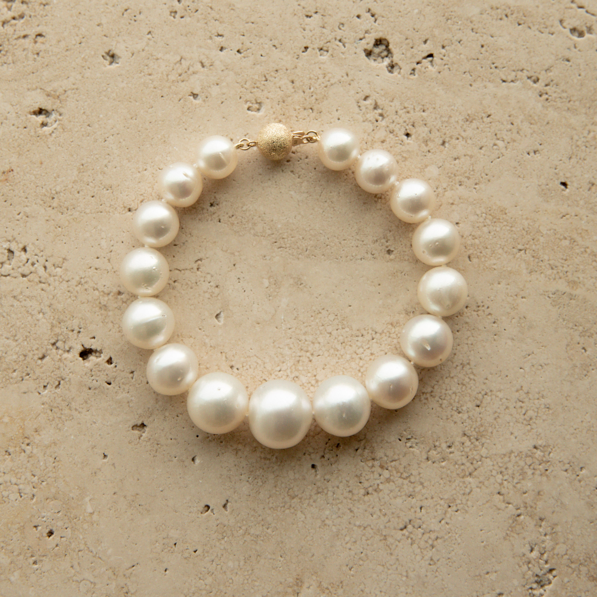 Graduated pearl strand bracelet on a textured beige surface 