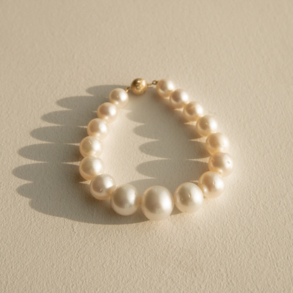 Graduated pearl strand bracelet on a textured beige surface 