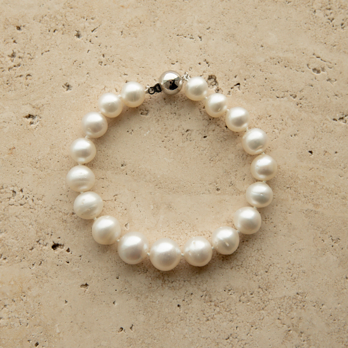 Pearl strand bracelet on a textured beige surface