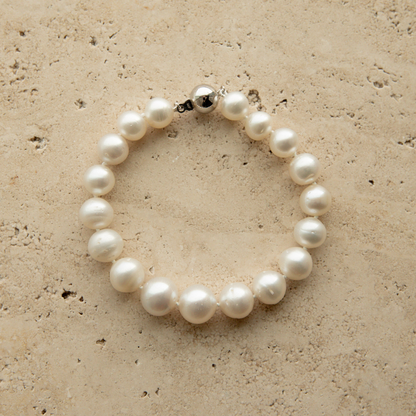 Pearl strand bracelet on a textured beige surface