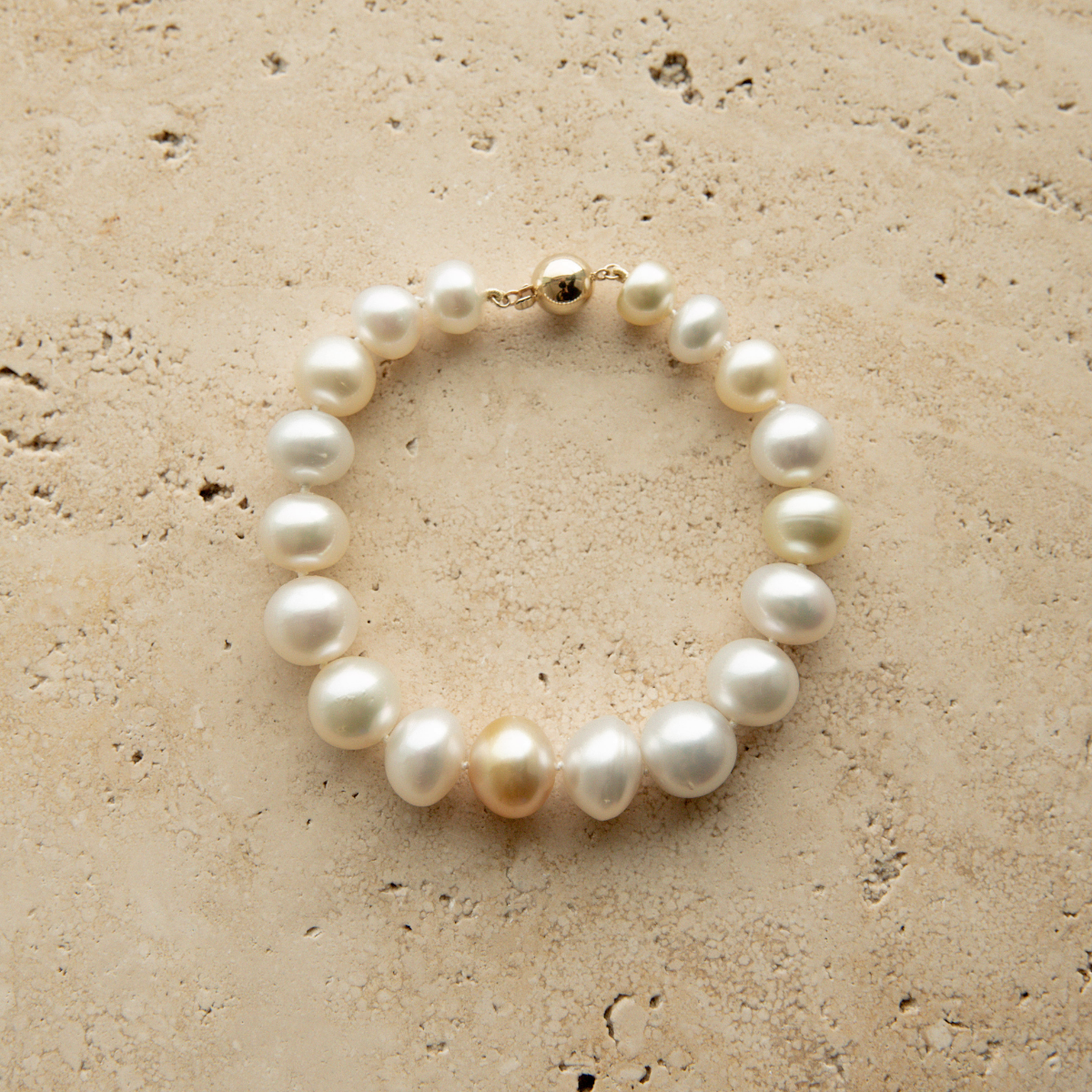 Multicolour pearl strand bracelet on a textured beige surface