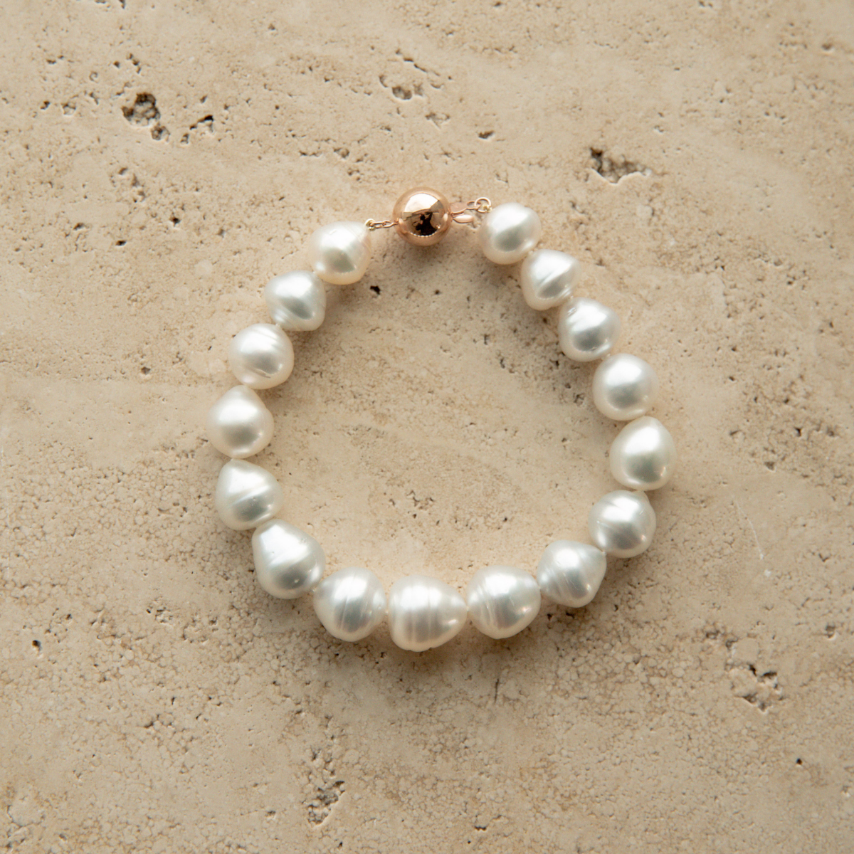 Pearl strand bracelet on a textured beige surface