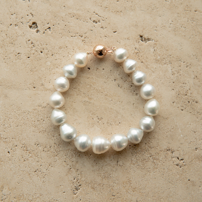 Pearl strand bracelet on a textured beige surface