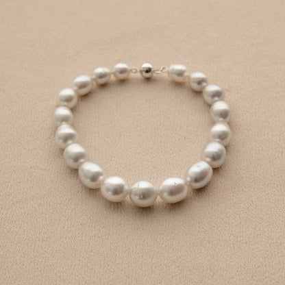 An Australian South Sea pearl strand bracelet with a 9ct white gold ball clasp, displayed on a textured beige surface.