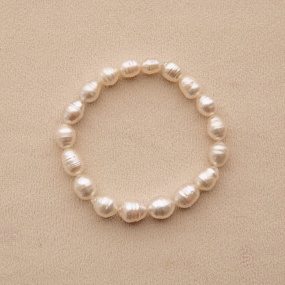 An elasticated pearl strand bracelet made of circle shape Australian Suth Sea pearls, displayed on a textured beige background.