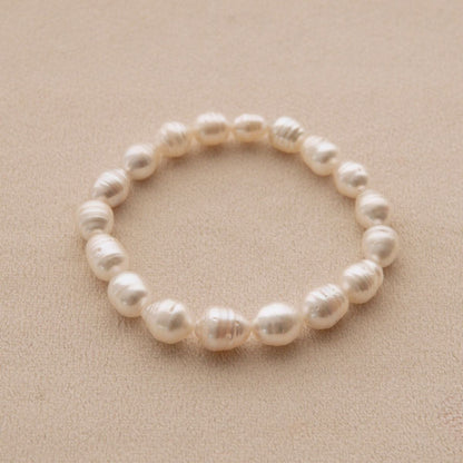 A strand bracelet made of circle shape Australian South Sea pearls, displayed on a textured beige background.