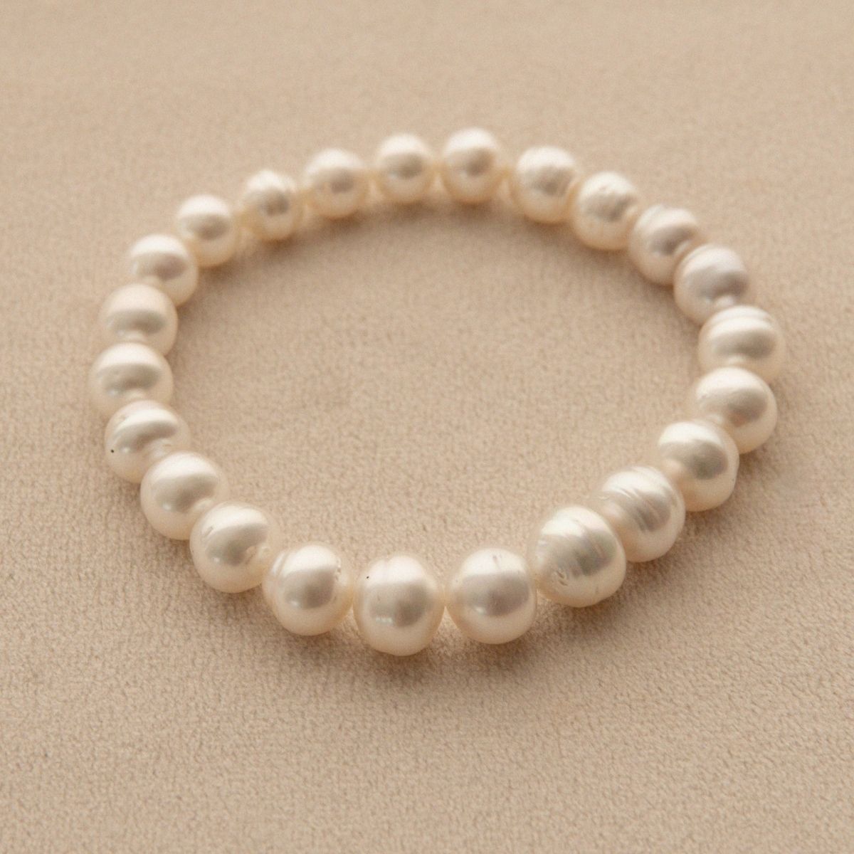 A pearl strand bracelet featuring circle shaped Australian South Sea pearls, displayed on a textured beige background.