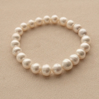 A pearl strand bracelet featuring circle shaped Australian South Sea pearls, displayed on a textured beige background.