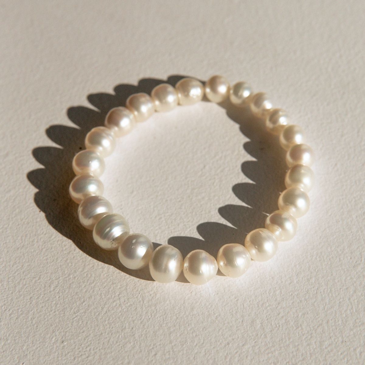 Australia South Sea pearls, arranged in a circle on a textured beige surface with a soft shadow.
