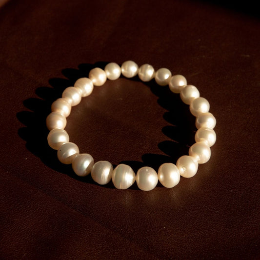 A pearl strand bracelet featuring Cygnet Bay grown Australian South Sea pearls arranged in a circle on a dark brown textured surface.