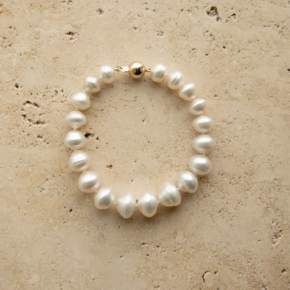 Pearl strand bracelet on a textured beige surface