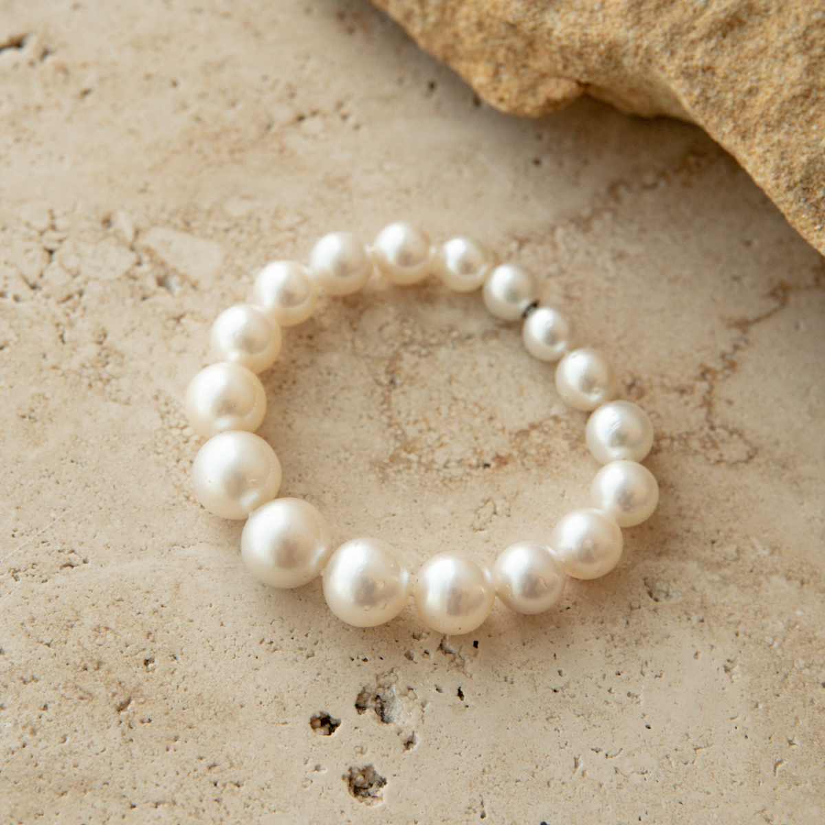 South Sea pearl strand bracelet on a textured beige surface