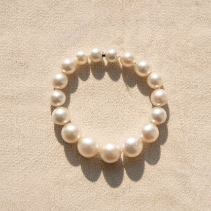 Pearl strand bracelet on a beige fabric background