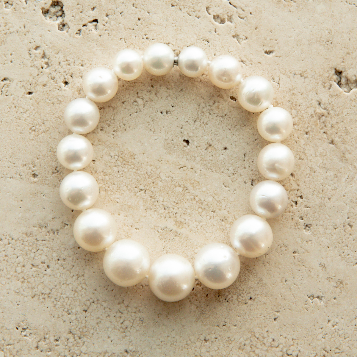 Pearl strand bracelet on a textured beige surface