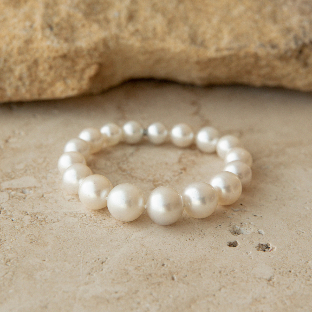 Pearl strand bracelet on a textured beige surface