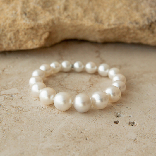 Pearl strand bracelet on a textured beige surface