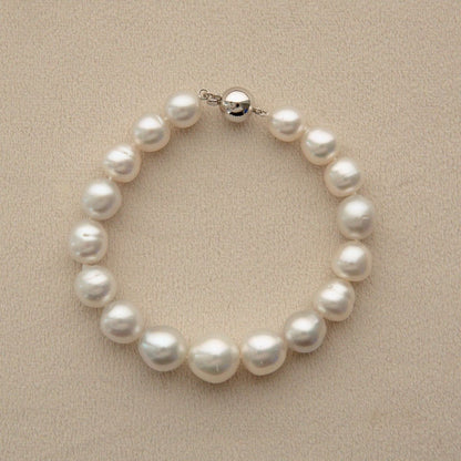 A Saltwater pearl bracelet with irregular white Australian South Sea pearls grown at Cygnet Bay Pearl Farm and a 9ct white gold clasp, displayed on a textured beige background.