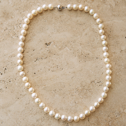 Pearl strand necklace on a textured beige surface