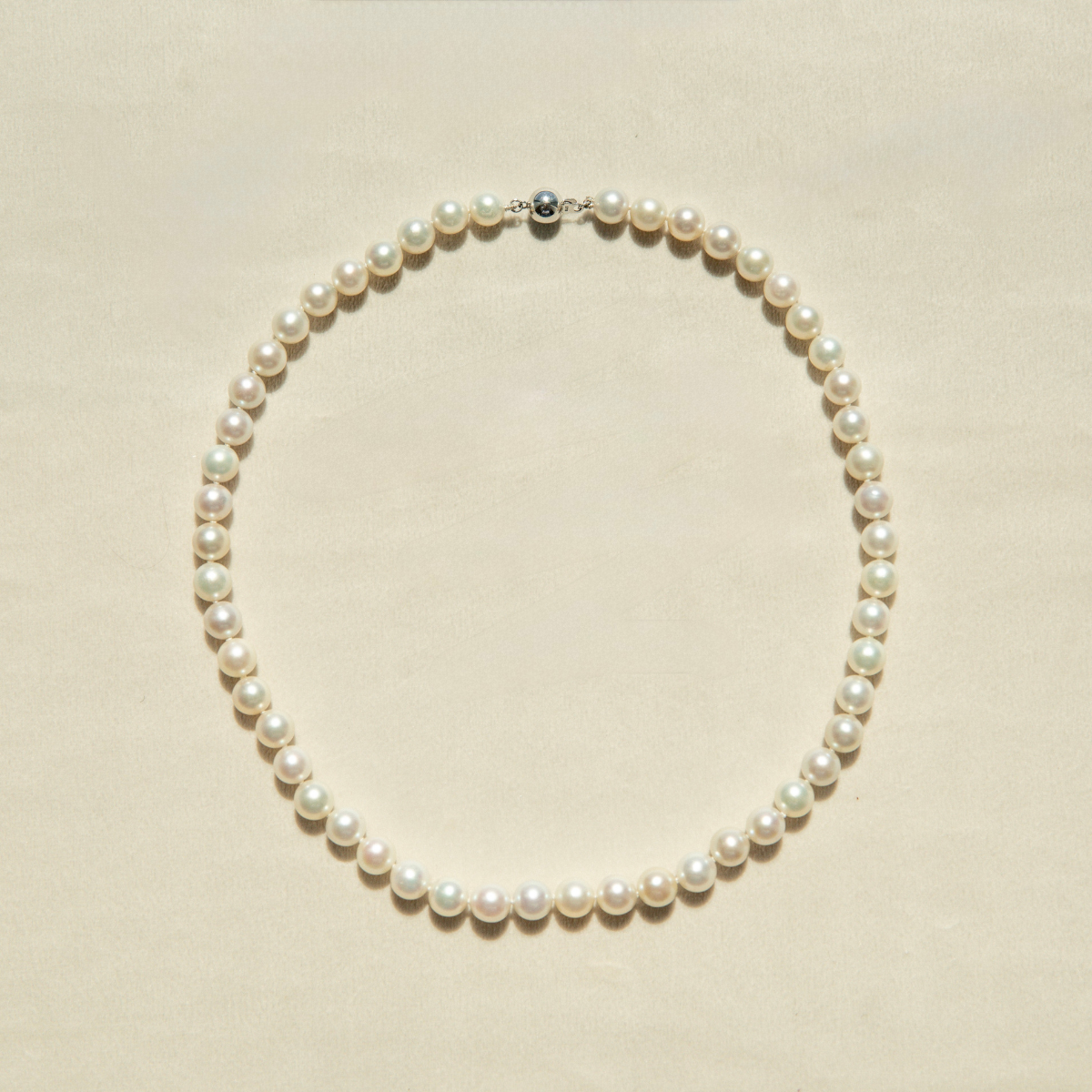 Pearl strand necklace on a beige background