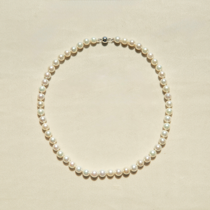 Pearl strand necklace on a beige background