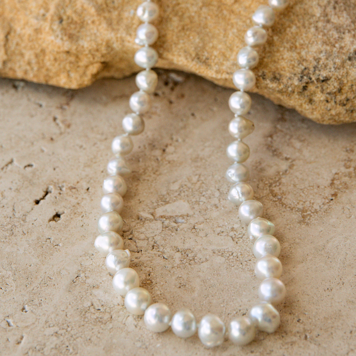 Pearl strand necklace on a textured stone surface