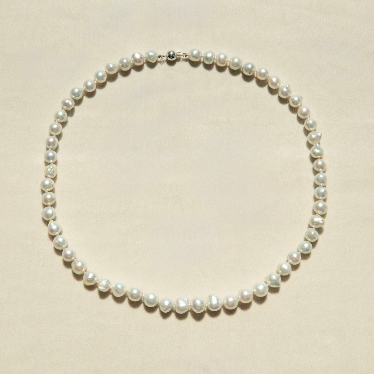 Pearl strand necklace on a beige background
