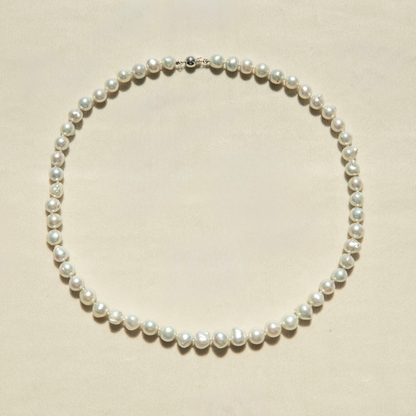 Pearl strand necklace on a beige background