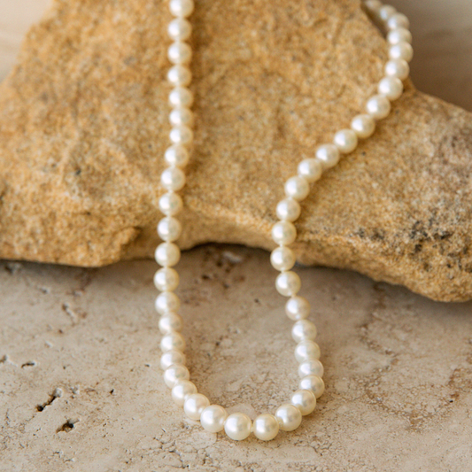 Pearl strand necklace on a textured stone surface