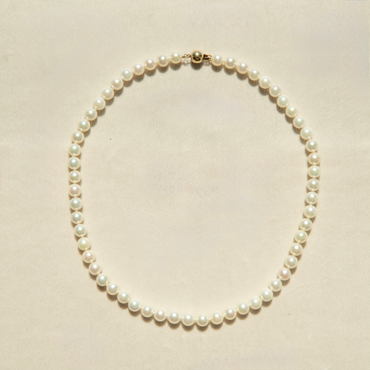 Pearl strand necklace on a beige background