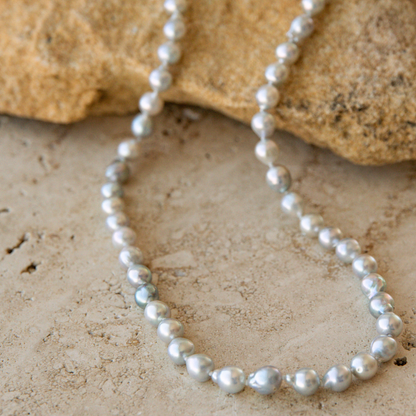 Pearl strand necklace on a textured stone surface