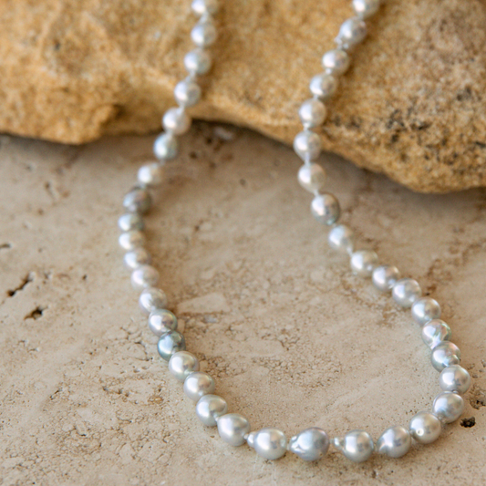 Pearl strand necklace on a textured stone surface