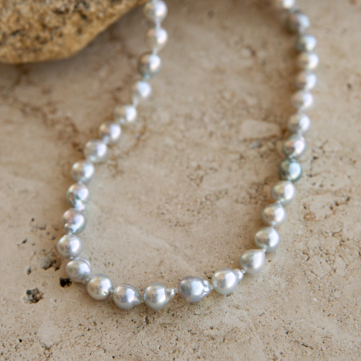 Pearl strand necklace on a textured beige surface