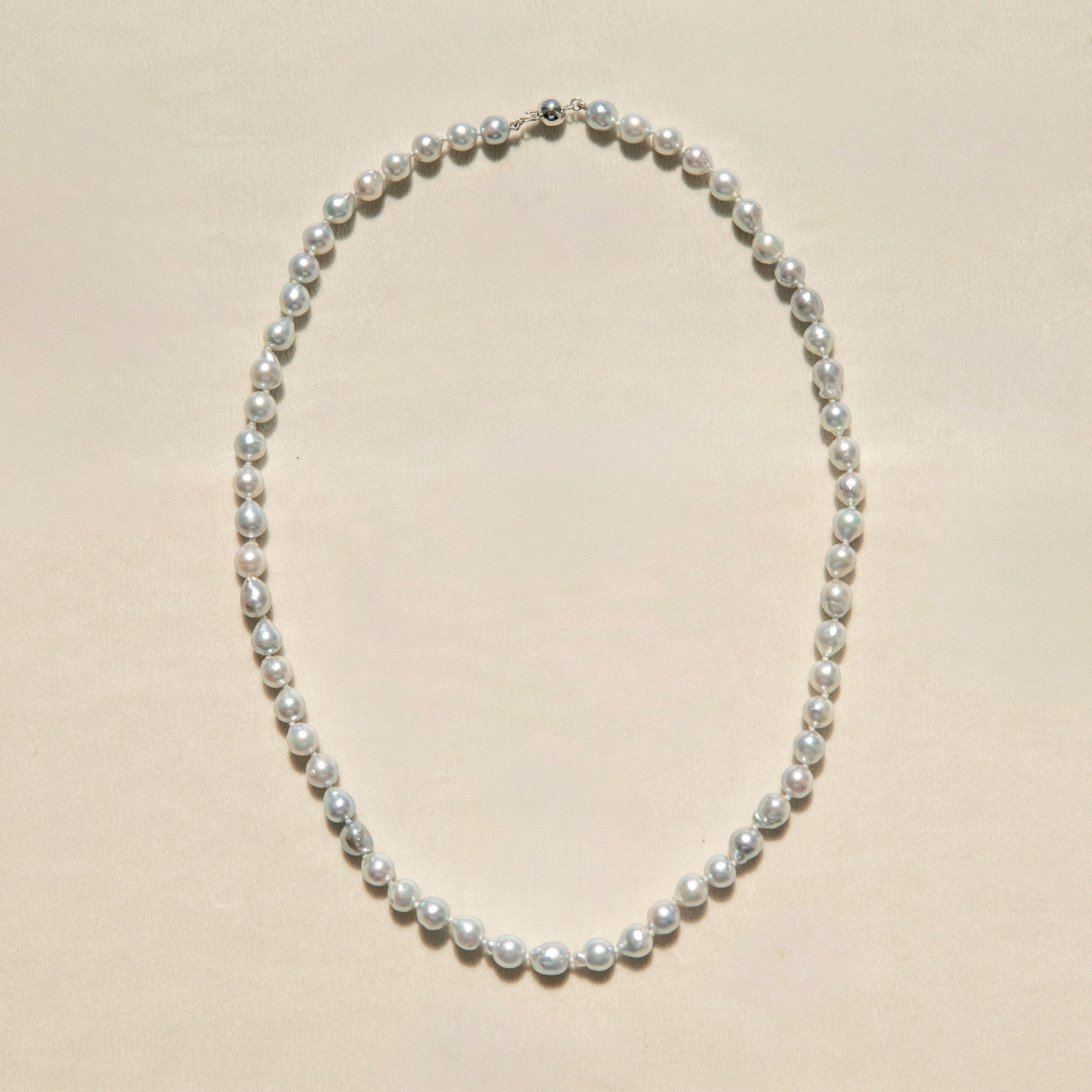 Pearl strand necklace on a beige background
