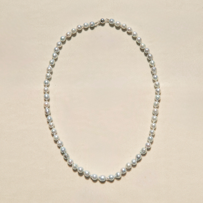 Pearl strand necklace on a beige background