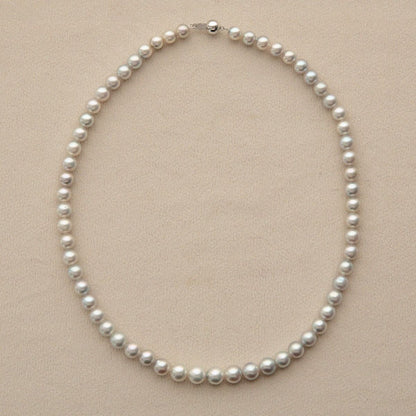 A classic Australian pearl strand necklace with uniform white pearls and a 9ct white gold clasp, displayed on a neutral beige textured background.