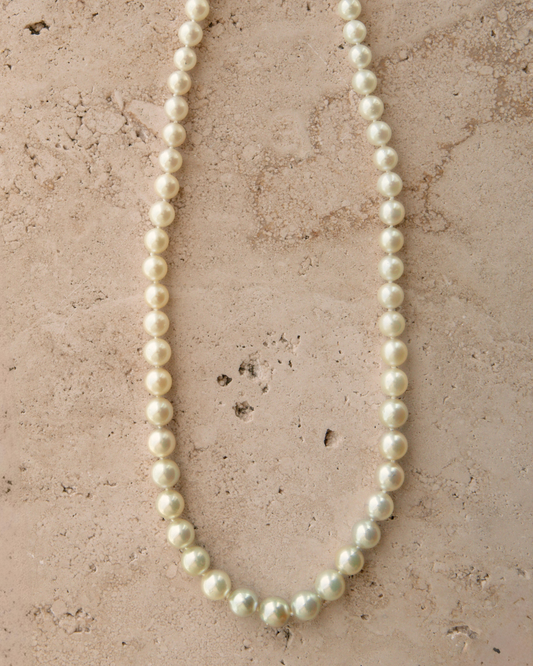 Pearl necklace on a textured beige surface