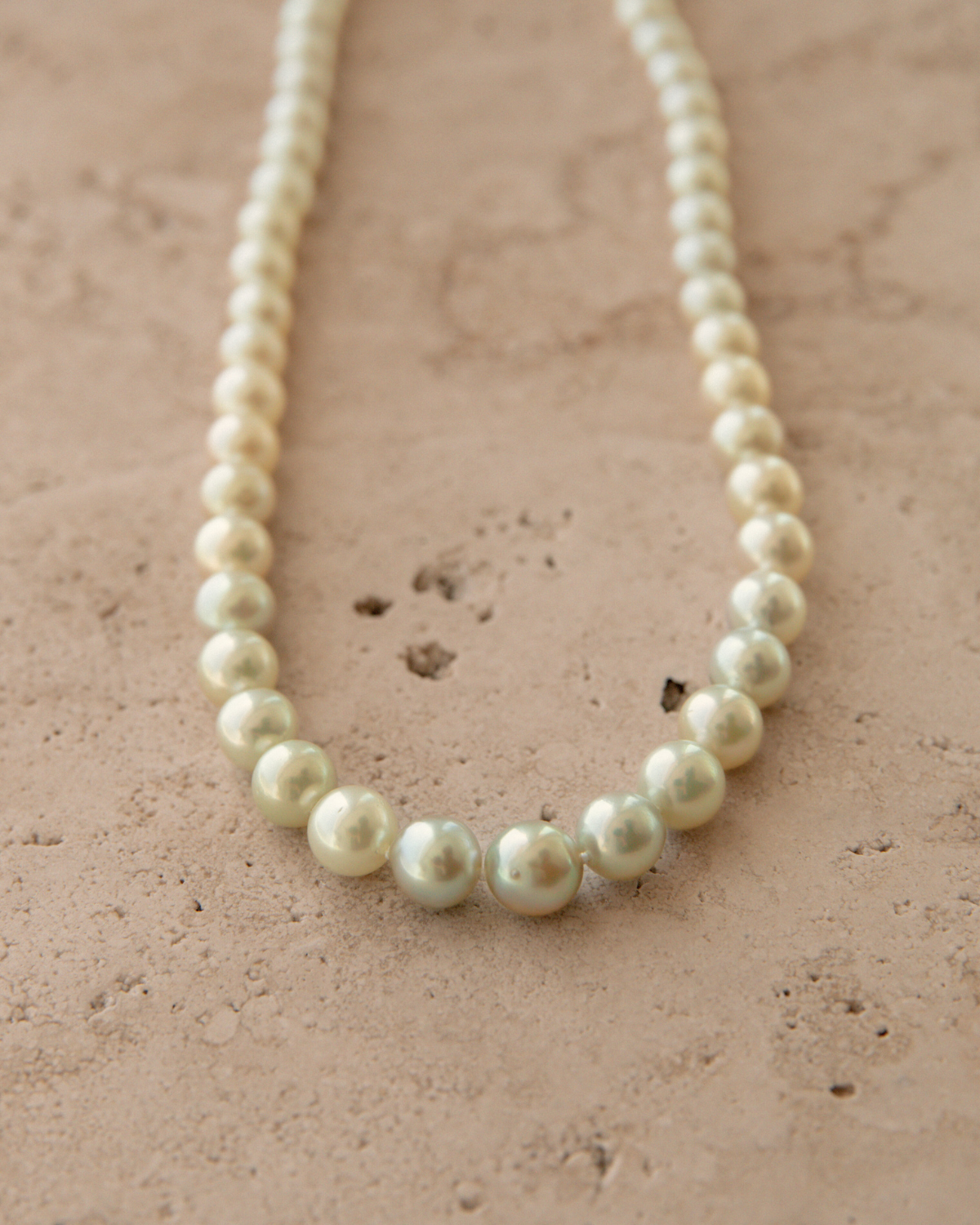 Pearl necklace on a textured beige surface