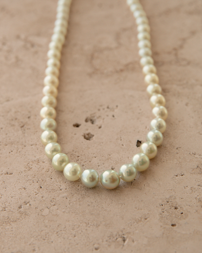 Pearl necklace on a textured beige surface